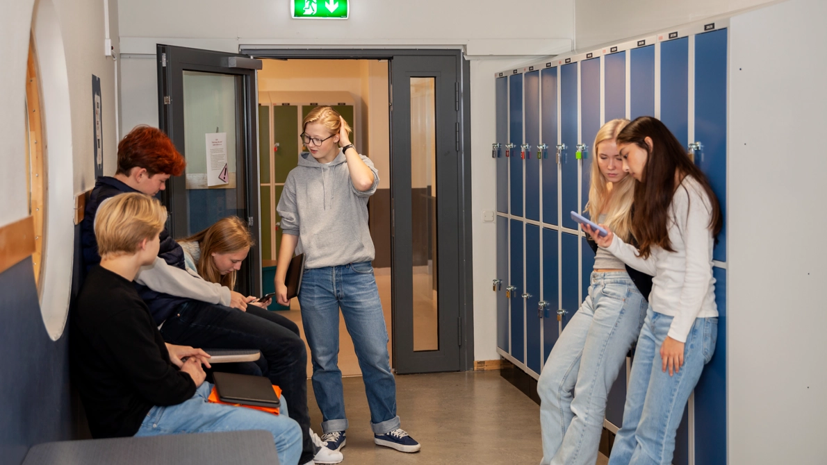 Flera gymnasieungdomar i en korridor med skåp.
